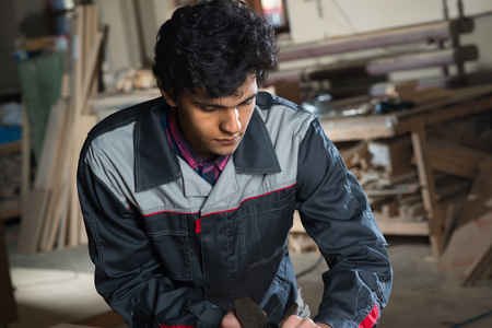 Young craftsman in uniform working at carpentryの写真素材