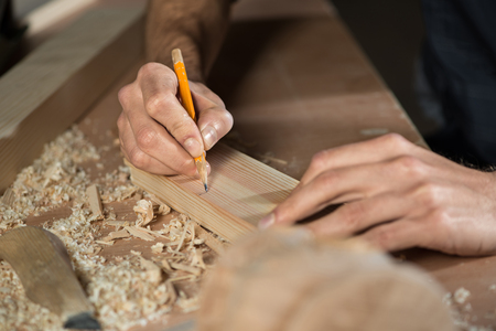 Close up carpenter\'s hands that work with cutterの写真素材