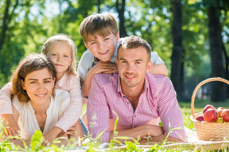 Happy family of four lying in summer parkの写真素材