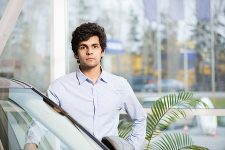 Young handsome man at show room standing near carの写真素材