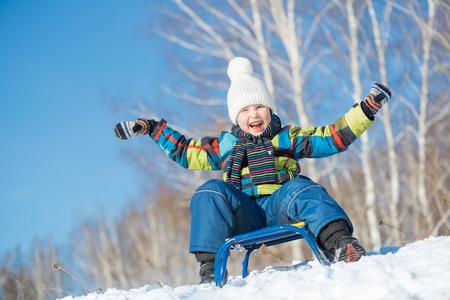 Little cute boy riding sled in winter parkの写真素材