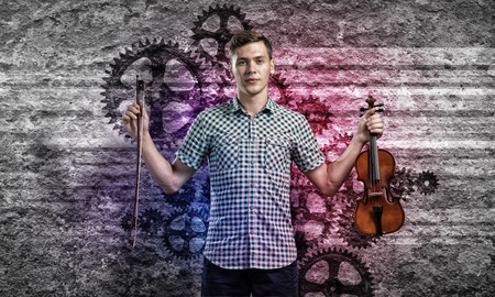 Young handsome guy in shirt playing violin