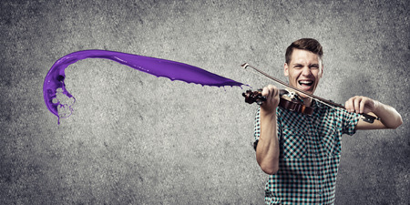 Young handsome guy playing violin very emotionallyの写真素材