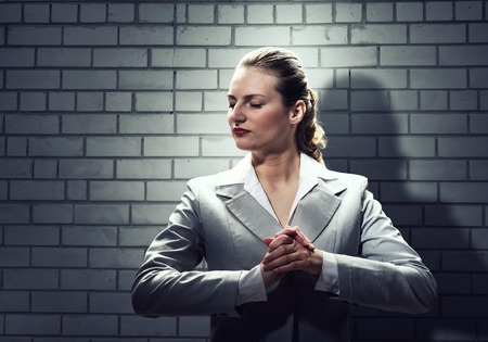 Young saint businesswoman praying with hands on chestの写真素材