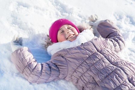 Top view of cute girl lying on snowの写真素材