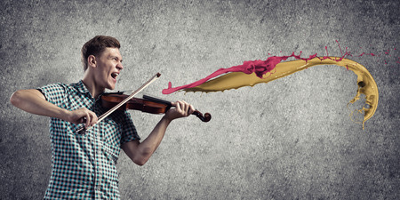 Young handsome guy playing violin very emotionallyの写真素材