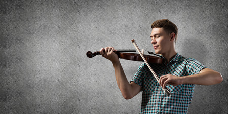 Young handsome guy in shirt playing violin