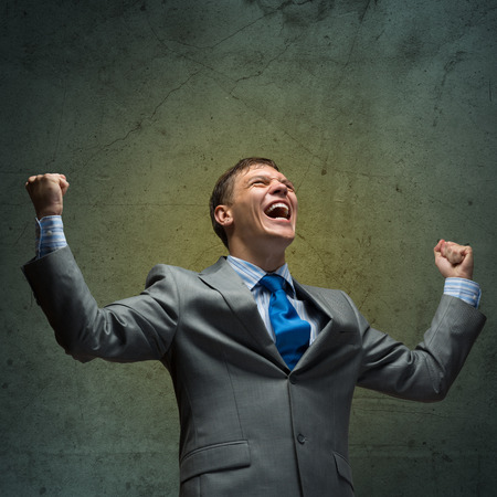 Young joyful businessman screaming with hands upの写真素材