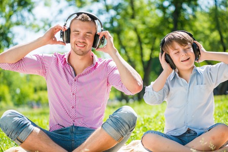 Father and kid in summer park enjoying musicの写真素材