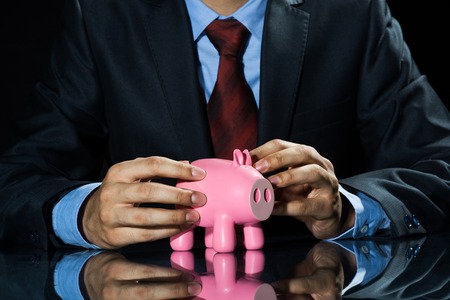 Businessman holding pink piggy bank in hands