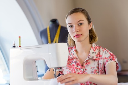Young attractive needlewoman at studio working with sewing machineの写真素材
