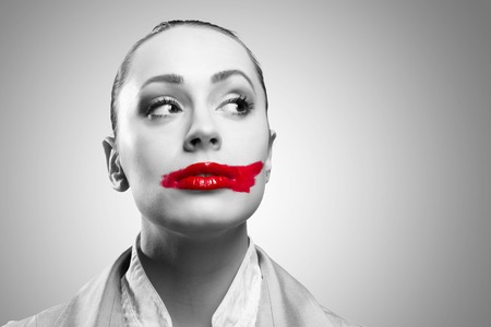 Conceptual black and white image of a young woman with vivid red mouthの写真素材