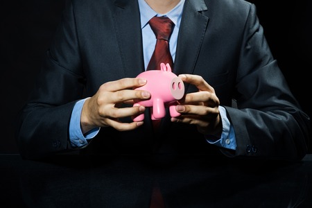 Businessman holding pink piggy bank in handsの写真素材