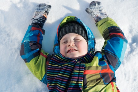 Top view of cute boy lying on snow