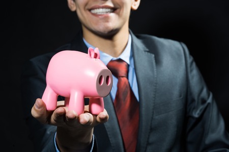 Businessman holding pink piggy bank in handsの写真素材