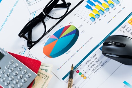 Close of business workplace with financial reports and office stuffの写真素材