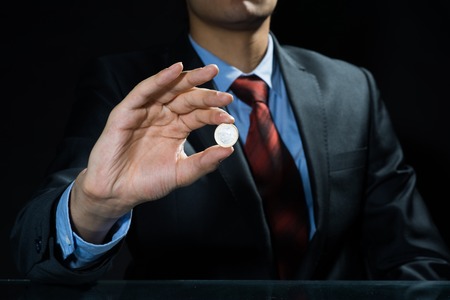 Close up of businessman holding coin in handの写真素材
