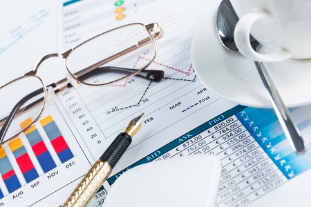 Close of business workplace with financial reports and office stuffの写真素材