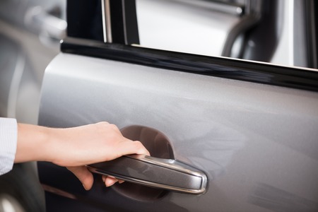Close up of human female hand opening car doorの写真素材
