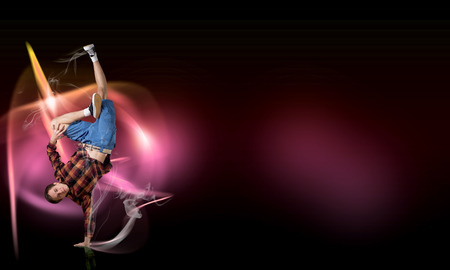Young breakdancer performing a hand stand on color background