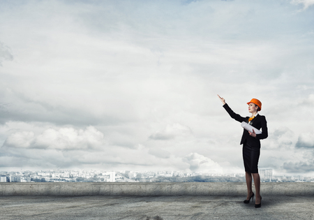 Young woman architect in hardhat holding project in handの写真素材
