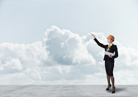 Young woman architect in hardhat holding project in handの写真素材