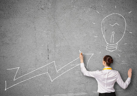 Rear view of businesswoman drawing increasing graphの写真素材