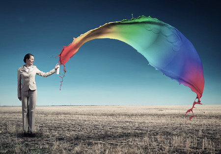 Young businesswoman with suitcase using spray balloonの写真素材