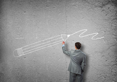 Rear view of businessman drawing sketches on wallの写真素材