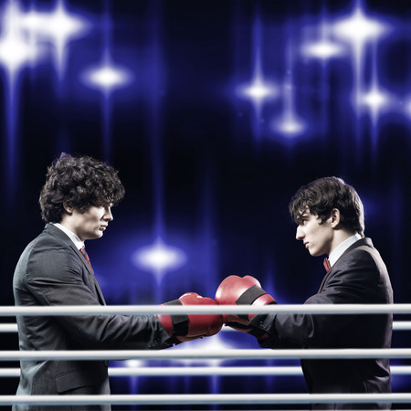 Two businessman with boxing gloves in the ring fighting with each other