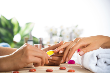 Woman in salon receiving manicure by nail beauticianの写真素材