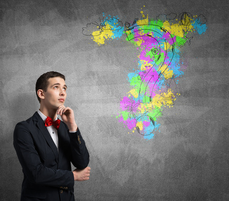 Young thoughtful man and sketches on wallの写真素材