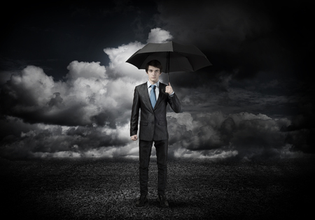 Young businessman in black suit with umbrellaの写真素材