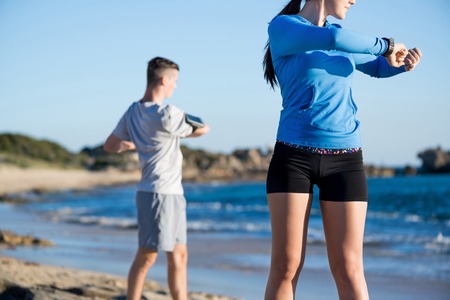 Young couple of man and woman stretching on ocean beachの写真素材