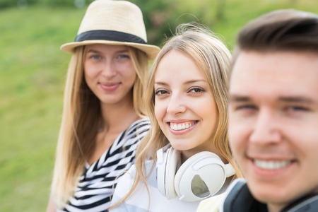 Three young happy people sitting on staircase and enjoying summer day