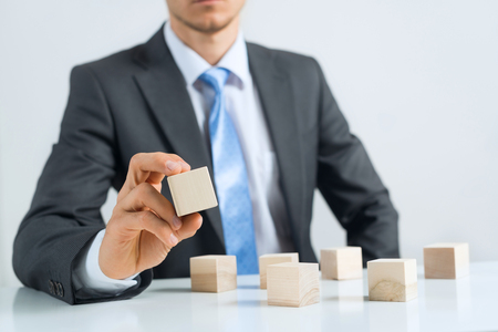 Close up of businessman building tower of wooden blocksの写真素材