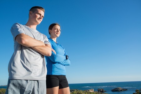 Young active couple of joggers on beach taking breathの写真素材