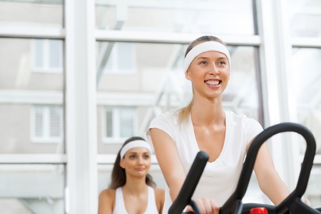 Small group of young people exercising on bikes in fitness centerの写真素材