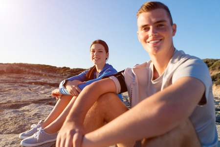 Young active couple of joggers on beach taking breathの写真素材