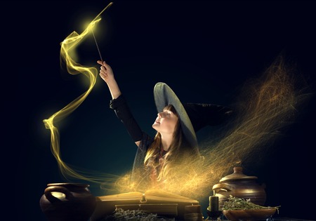 Little Halloween witch reading conjure from magic book above pot