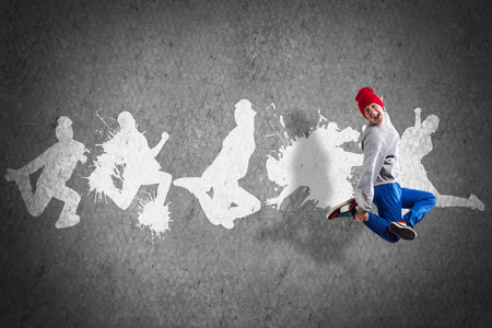 Young hip hop dancer in jump and silhouettes on gray wallの写真素材