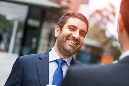 Two businessmen talking outdoors while taking coffee breakの写真素材
