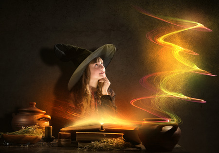 Little Halloween witch reading conjure from magic book above potの写真素材