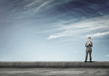 Young businessman on building top playing trumpetの写真素材