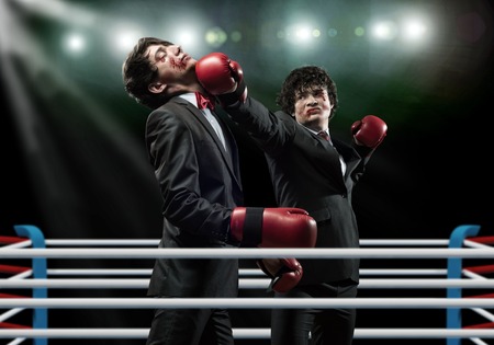 Two businessman in boxing gloves in ring fighting with each otherの写真素材