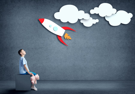 Kid boy holding bear toy and dreaming to become astronautの写真素材