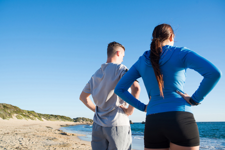 Young active couple of joggers on beach taking breathの写真素材