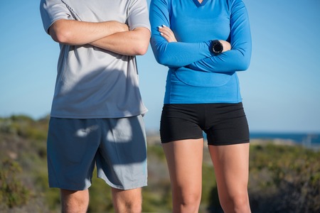 Young active couple of joggers on beach taking breath