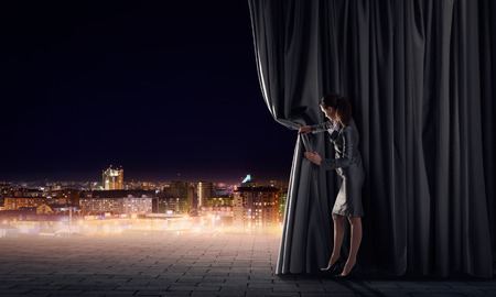 Young woman in business suit opening color curtain of stageの写真素材