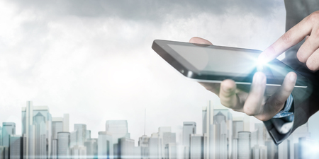 Close up of businessman using tablet pc and city landscape at backgroundの写真素材